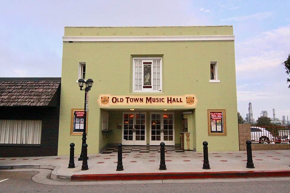 The green front of Old Town Music Hall on Richmond Street, refinery towers visible over the roofline behind it.