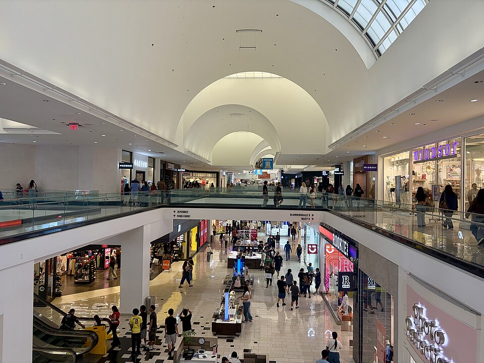 A two-level atrium inside the Glendale Galleria under a barrel-vaulted skylight, with Bloomingdale's and Macy's signs overhead.