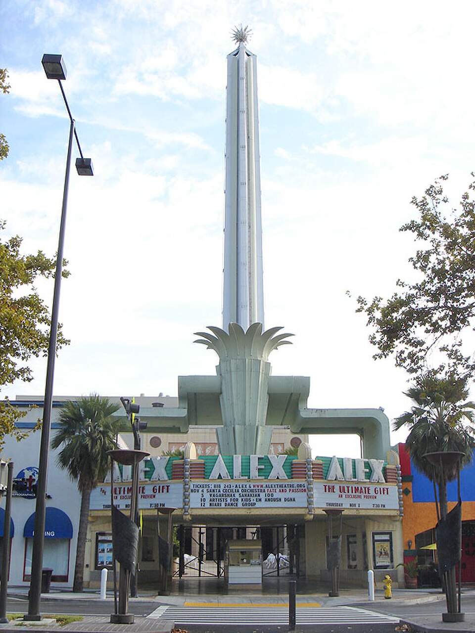 The Alex Theatre's marquee and tall neon tower on North Brand Boulevard, palm trees on both sides of the entrance.