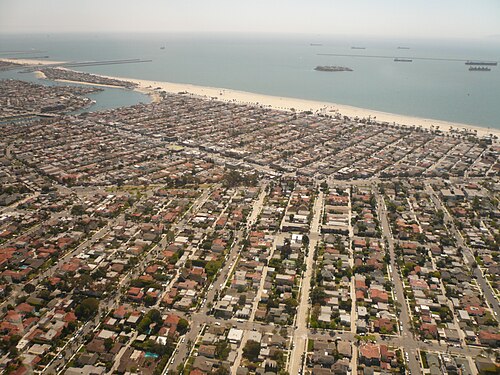 An aerial view of the coast looking southeast, Belmont Heights closest to the camera and Belmont Shore's grid of streets and beach farther along toward Alamitos Bay.