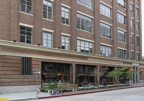 The National Biscuit Company building on Industrial Street at dusk, its name in raised letters above a row of restaurant windows lit up at street level, bicycles parked out front.