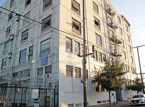 A pale, multistory loft building on the 1300 block of East 6th Street, fire escapes zigzagging up one corner and a lots for rent sign on the wall.