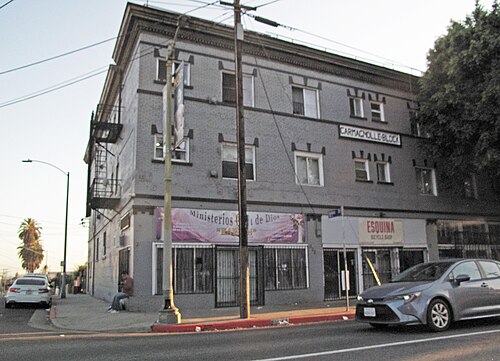 A brick corner building at 2228 Whittier Boulevard, the Esquina Bicycle Shop and a storefront church at street level.