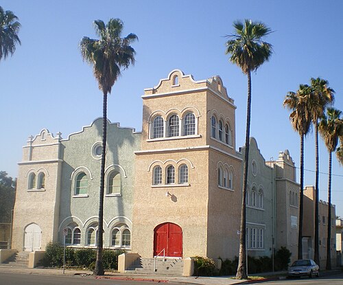 Faith Calvary Baptist Church on St. Louis Street, a two tower stucco building with round arched windows and palm trees in front.