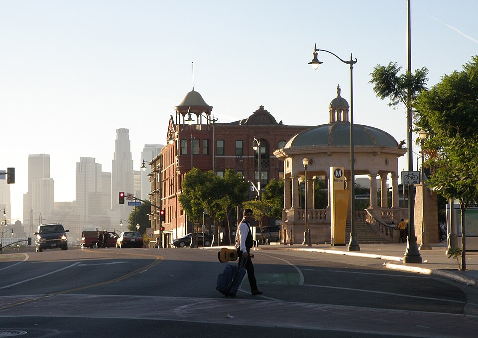Mariachi Plaza's tiled kiosko and the Metro station stair, the Boyle Hotel's corner tower and downtown Los Angeles behind.