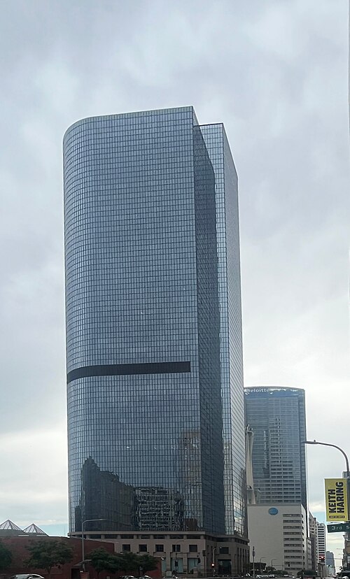 One California Plaza's curved glass tower rising above the street, seen from below.