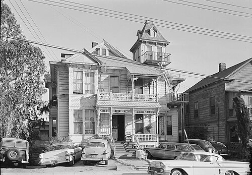 A Bunker Hill Victorian house photographed in 1960 for the Historic American Buildings Survey, a corner tower above a wraparound porch, cars from the period parked on the street.