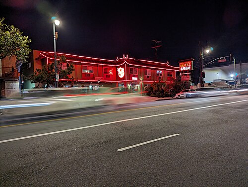 The Royal Pagoda Motel on North Broadway at night, its tiled roofline outlined in red neon, headlights streaking past on the street below.