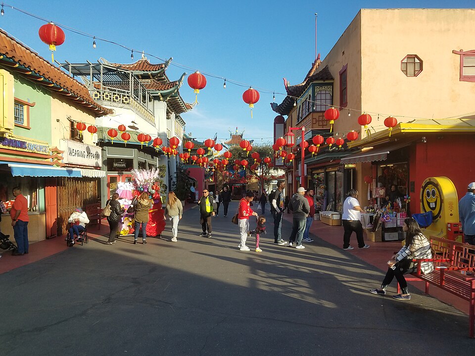 Chung King Road, paper lanterns strung between a pagoda roofed building and rows of shops, benches along the sidewalk.
