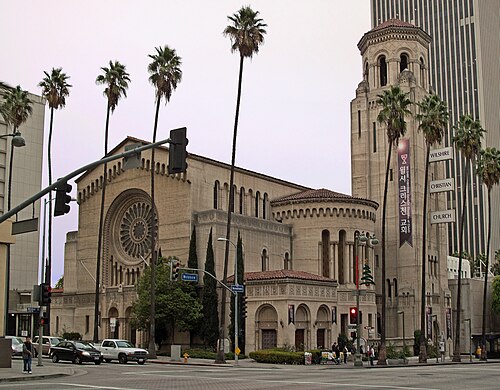Wilshire Christian Church at Wilshire Boulevard and Normandie Avenue, a domed bell tower behind tall palm trees, with a Korean-language banner for the same congregation on the tower.