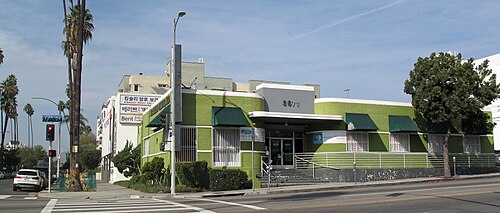 A green Streamline Moderne medical building on Sixth Street with striped awnings and signs lettered in Korean.