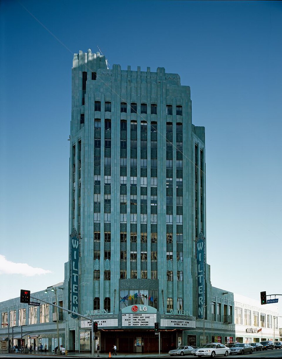 The Wiltern's teal terra cotta tower at Wilshire Boulevard and Western Avenue, its stepped Art Deco profile against a clear sky.