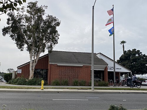 The Lloyd Taber Marina del Rey Library, a low brick building with a pitched tile roof and a flagpole out front.