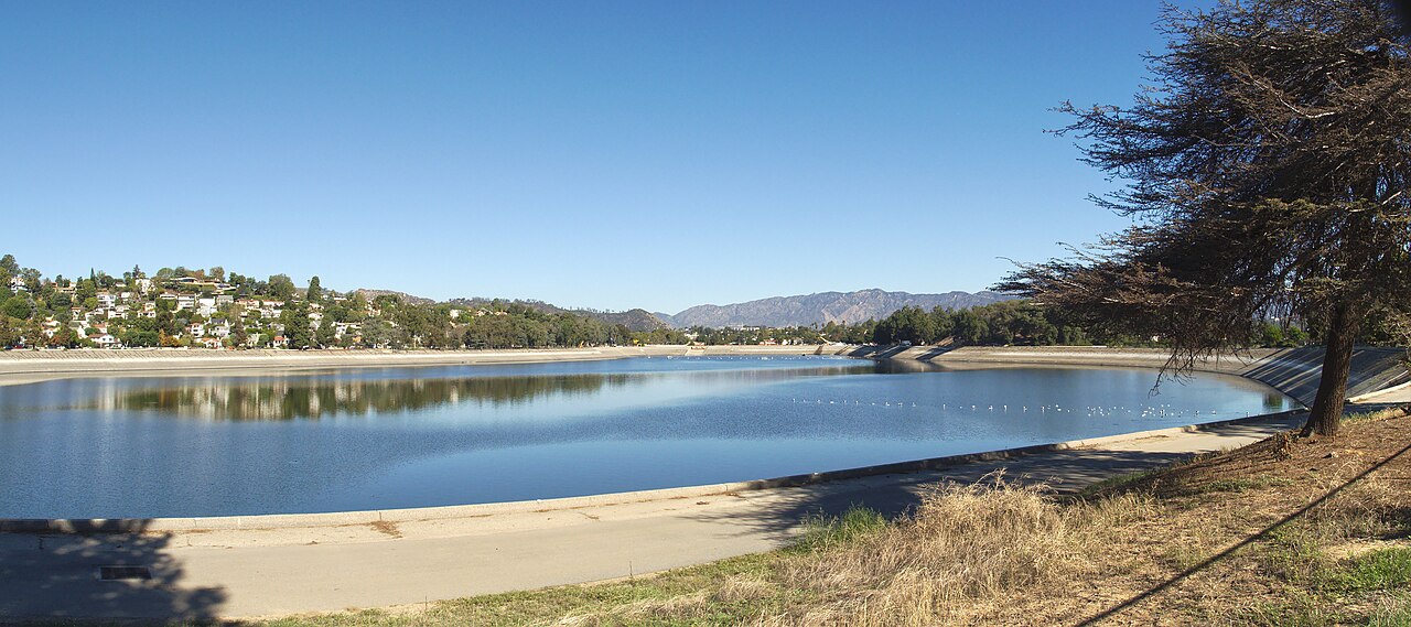 The Silver Lake Reservoir looking northwest, hillside houses along the far bank, mountains behind, and the paved path that rings the water.
