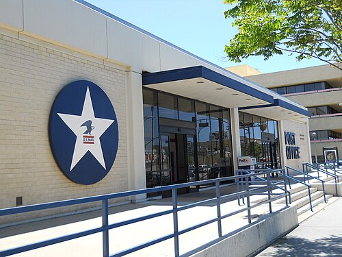 The Van Nuys Government Center post office, a low brick building with a blue and white U.S. Mail seal beside the entrance.
