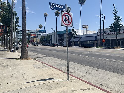 Van Nuys Boulevard at the Archwood Street corner, palm trees along the sidewalk and storefronts including a Citibank branch across the street.