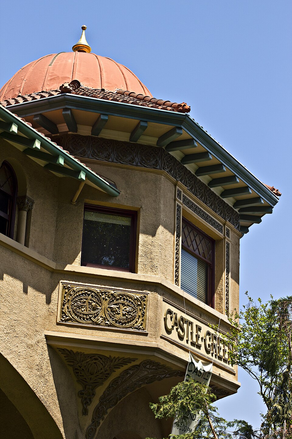 The Castle Green name carved into gold lettering under one of the building's red tile domes, looking straight up at the turret.