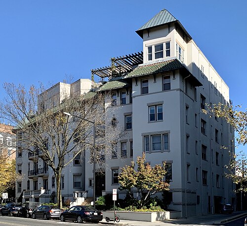 The Kalorama apartment building on Columbia Road, an off white corner tower with a tiled roof over bay windows and cars parked along the curb.