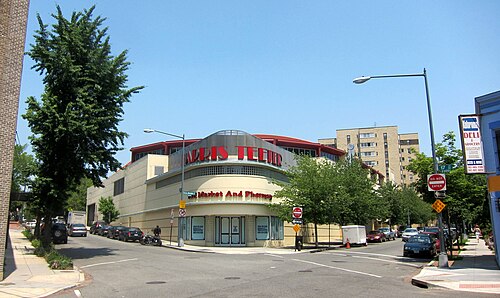 A curved Streamline Moderne supermarket building on Kalorama Road, cream stucco under a red band and a red grocery sign wrapped around the corner.