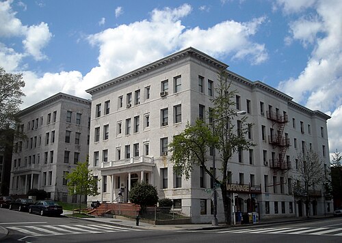 Two white brick apartment buildings on Wyoming Avenue, a columned entrance portico and iron fire escapes climbing the side elevation.