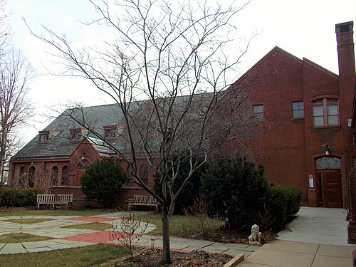 St. Mark's Episcopal Church, a red brick bell tower and sanctuary behind clipped hedges and a brick paved walk.