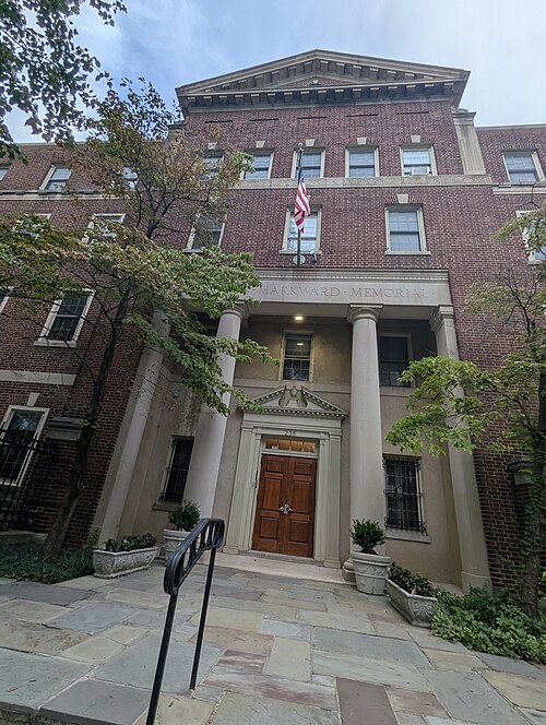 The columned brick entrance of Thompson-Markward Hall, double wood doors under a stone pediment and a flag overhead.