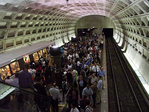 The Federal Triangle Metro platform under its coffered concrete vault, a train alongside the platform at rush hour.