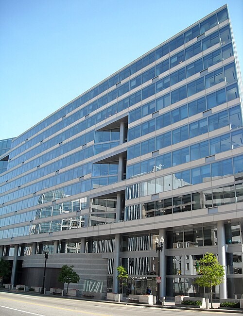 The International Monetary Fund's headquarters on Pennsylvania Avenue, a glass and steel office slab with a sharp angled corner and a colonnade of round columns at street level.