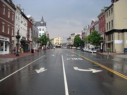 The commercial strip after rain, brick storefront rows on both sides.