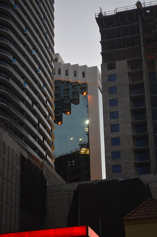 Modern glass high rise towers under construction surrounding an older reflective glass commercial building.