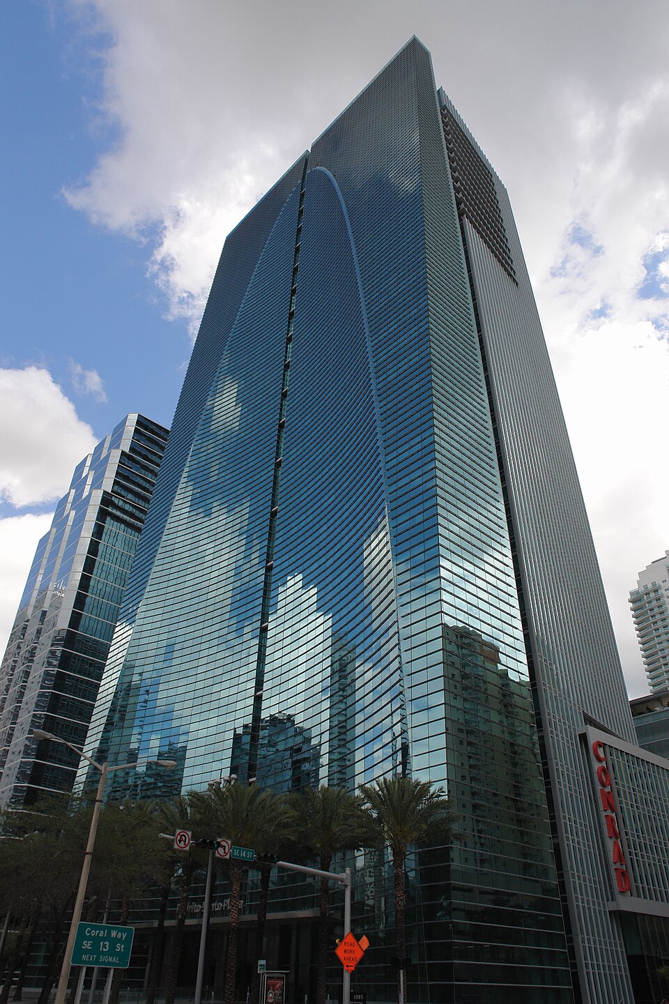 A low angle view of the Espirito Santo Plaza tower, its glass front curving into a concave arch under a cloudy sky.