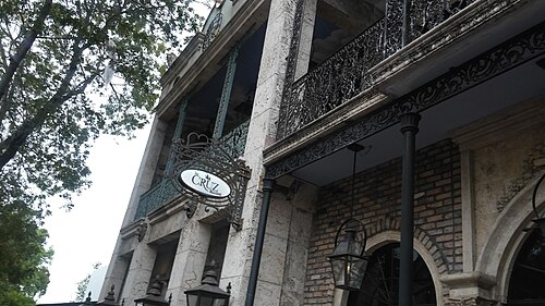 Upper floor coral stone and wrought iron balconies on the Cruz Building on Grand Avenue, brick arches below.