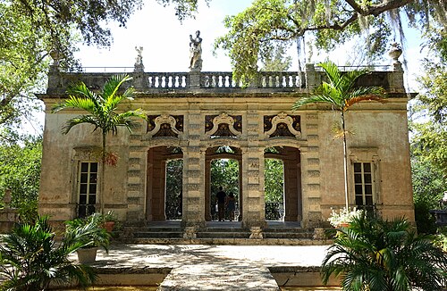 A garden pavilion at Villa Vizcaya, an open arched loggia in coral stone under live oaks draped with Spanish moss.