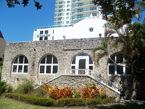 The coral rock Woman's Club of Coconut Grove, arched windows under a stepped parapet, a condo tower rising behind it.