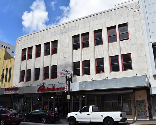 The McRory Building's cream stone facade on East Flagler Street, narrow fluted piers and red framed windows over a Rainbow clothing storefront at street level.