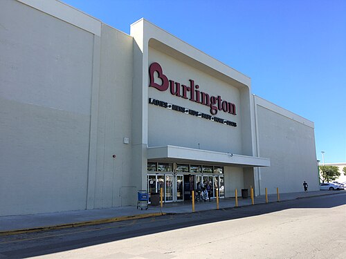 A rounded parapet marks the corner of a big box store on West 49th Street, now a Burlington, with double glass doors and a wide sidewalk out front.