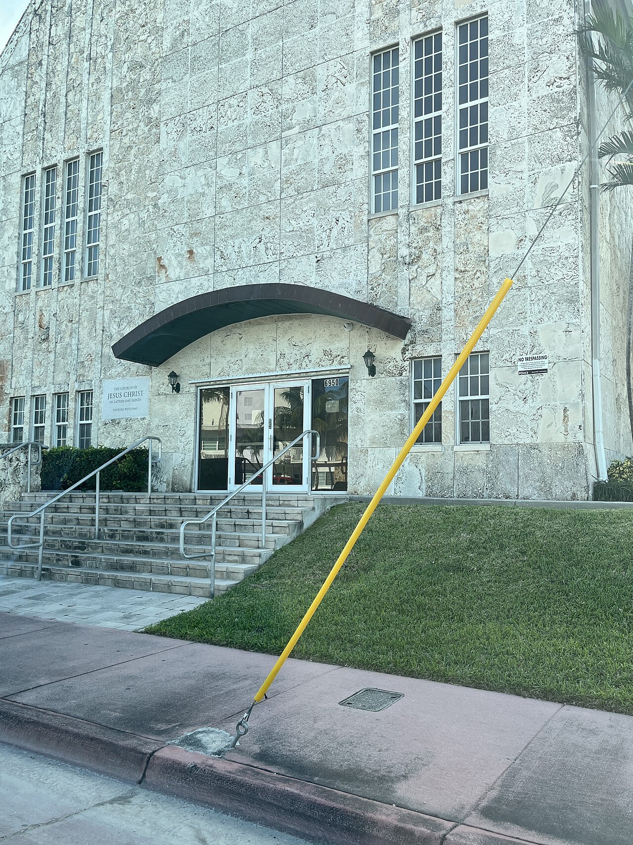 A travertine faced meetinghouse at 6950 Indian Creek Drive, a curved dark canopy over the entrance and tall vertical window bays.