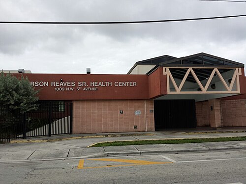 A brick institutional building with an angled canopy entrance, the health center's name across the fascia above 1009 NW 5th Avenue.