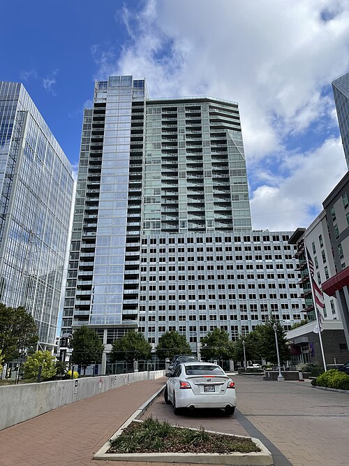 10 Terminus Place, a glass condominium tower in the office and hotel cluster along Peachtree Road, seen from below with two more towers alongside it.