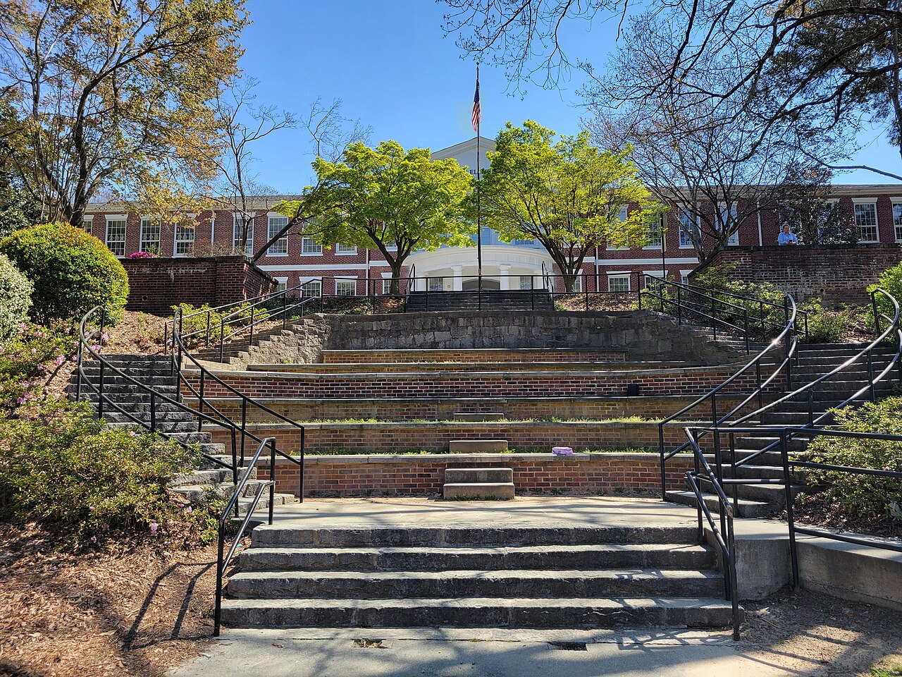 A brick amphitheater behind the elementary school, tiered steps leading up to the building and a flagpole.