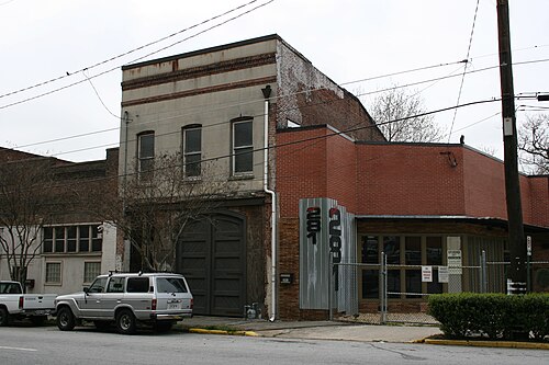 A two story brick and corrugated metal loft building with a garage door entrance and STUDIO painted on the side.