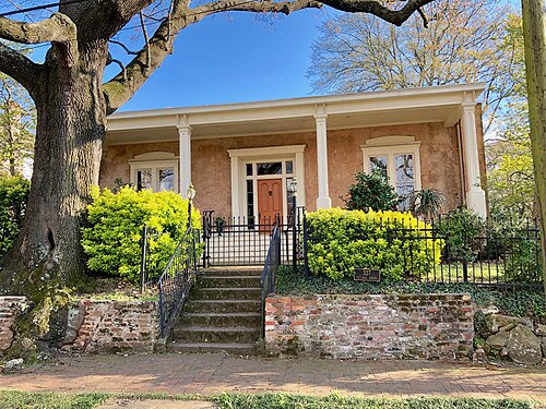 The L.P. Grant Mansion, a cream stucco house with four columns across the front porch, an oak tree overhanging the front yard.