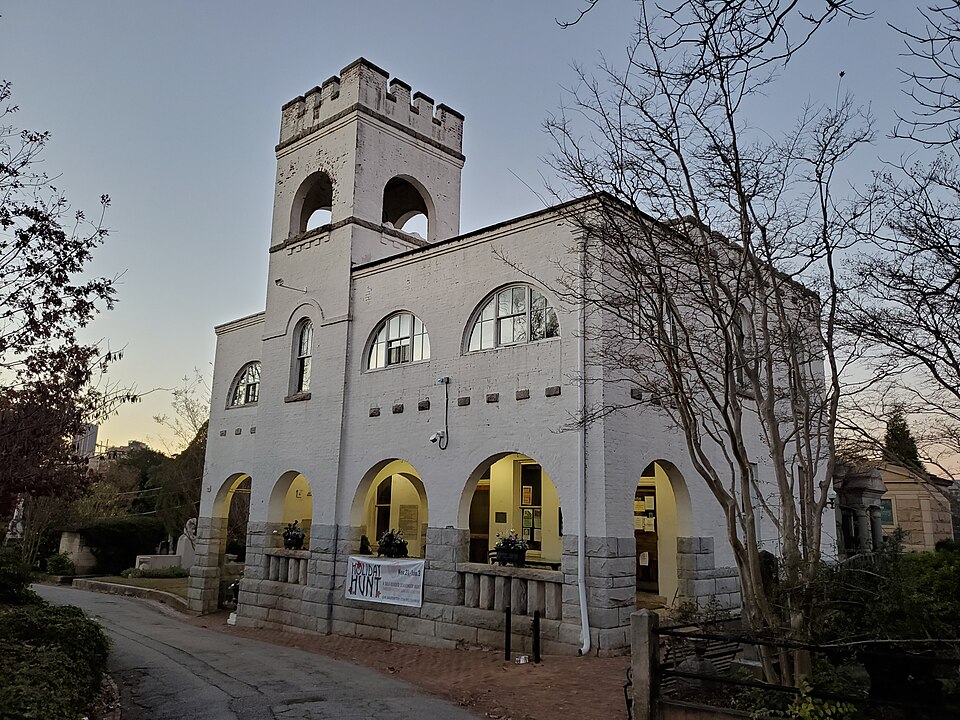 Oakland Cemetery's Bell Tower, a two-story stone and stucco building with a crenellated tower and an arcade of arches along the ground floor.