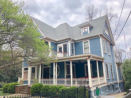 A pale blue Victorian on Euclid Avenue with a deep porch on turned columns, a balcony over it and a dormer in the roof.