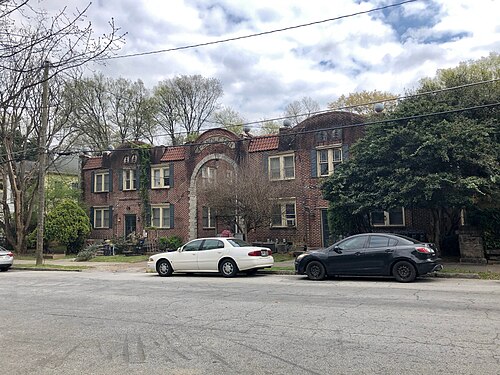 The Pendleton Apartments on Euclid Avenue, a two storey brick block with a tiled roof and an arched entrance in the middle, cars parked along the kerb in front of it.