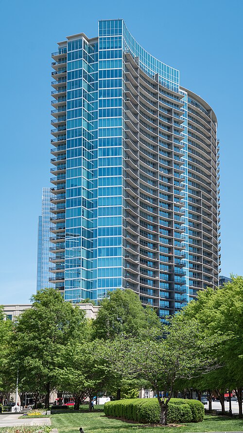 1010 Midtown, a curved blue glass condominium tower, seen from the plaza in front of the Federal Reserve building.