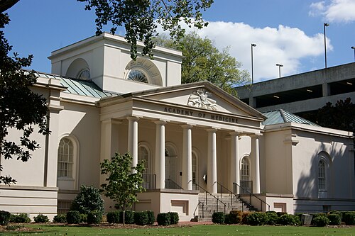 The Academy of Medicine building on West Peachtree Street, a white columned portico with the building's name carved above the entrance, a parking garage behind it.