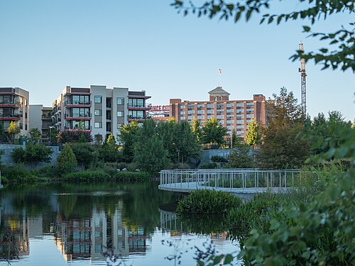 Ponce City Market across the pond in Historic Fourth Ward Park at sunset, the long brick Sears warehouse with its red roof sign and new apartment blocks on the left of it.