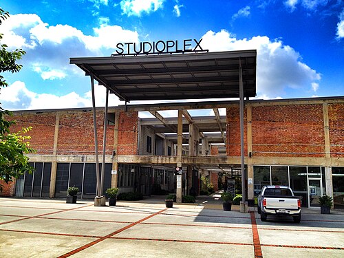 Studioplex on Auburn Avenue, a concrete framed industrial building with brick infill and a steel canopy over the entrance, an empty concrete forecourt in front.