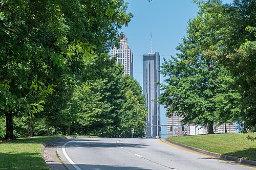 Freedom Parkway heading west toward Boulevard, an empty roadway between grass banks and trees with the round tower of the Westin at the end of it.